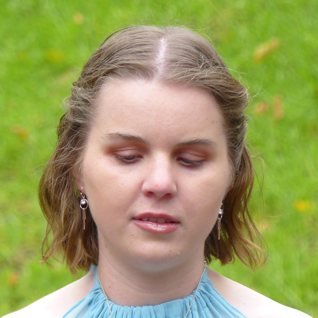 Headshot of a woman with short mid-brown hair and silver earrings - thoughtful expression